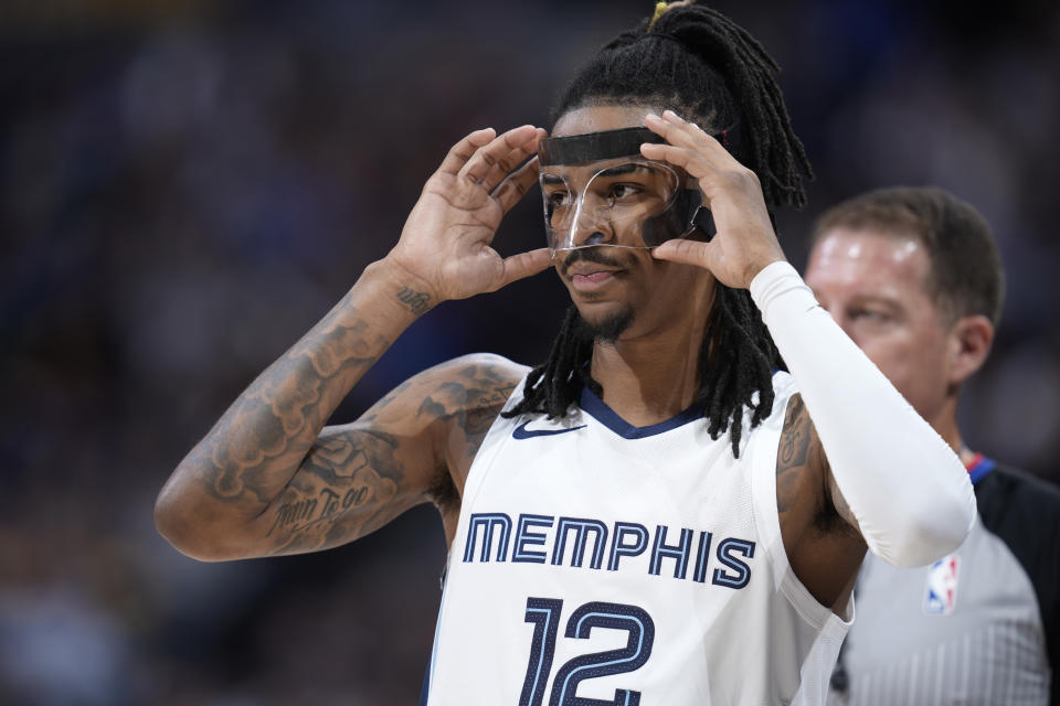 Memphis Grizzlies guard Ja Morant adjusts his protective mask in the first half of an NBA basketball game against the Denver Nuggets, Friday, March 3, 2023, in Denver. (AP Photo/David Zalubowski)