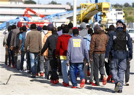 Migrants arrive and are escorted by Italian policemen at the Sicilian port of Augusta near Siracusa March 21, 2014. REUTERS/Antonio Parrinello