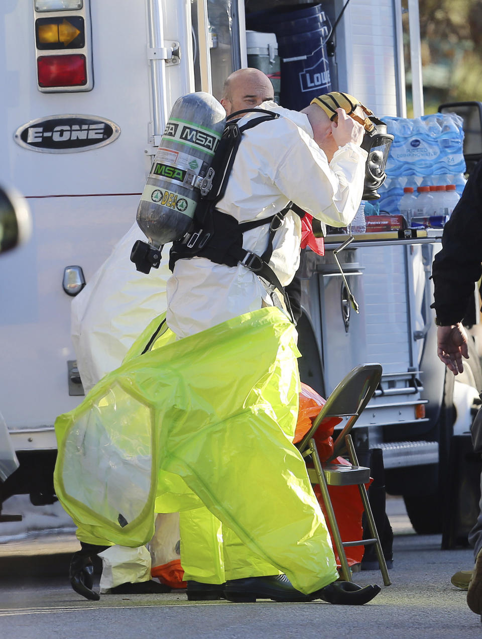 In this Nov. 22, 2016 photo, police and agents with the Drug Enforcement Administration put on protective gear as local and federal law enforcement agencies respond to a drug bust in Cottonwood Heights, Utah. The raid on Aaron Shamo’s home in the upscale suburb of Cottonwood Heights, agents found a still-running pill press in the basement, thousands of pills and more than $1 million in cash stuffed in garbage bags, according to court documents. (Scott G Winterton/The Deseret News via AP)