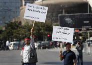 A retired Lebanese soldier, left, and his son, hold Arabic placards that read: "We are coming, oh enemies of honor, sacrifice and loyalty," and "You have robbed security from those who provide security," as they protest near the parliament building where lawmakers and ministers discussing the draft 2019 state budget, in Beirut, Lebanon, Tuesday, July 16, 2019. The lawmakers have begun discussing the draft 2019 state budget amid tight security and limited protests against proposed austerity measures. The proposed budget aims to avert a financial crisis by raising taxes and cutting public spending in an effort to reduce a ballooning deficit. (AP Photo/Hussein Malla)