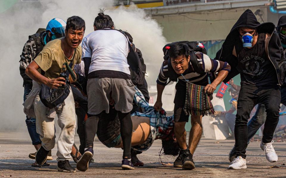 Protesters carry a wounded man shot with live rounds by security forces during a crackdown on demonstrations, August 2021 - AFP