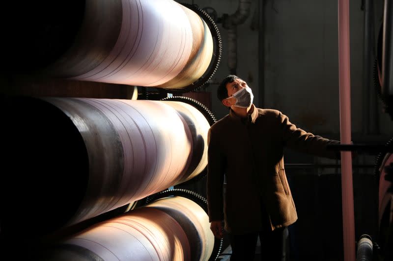 Employee wearing a face mask works on drying cloths at a textile factory in Hangzhou