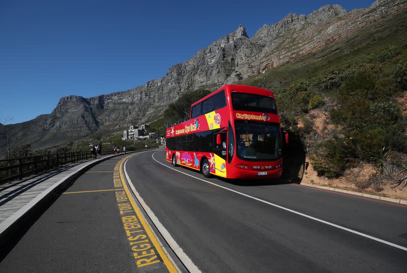 An almost empty tour bus drives below the city's iconic landmark Table Mountain in Cape Town