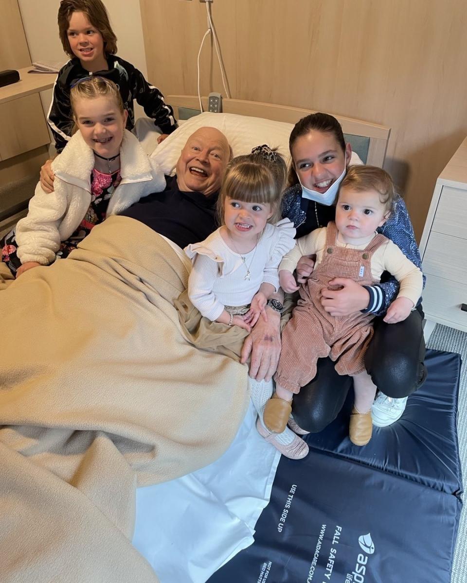 Bert Newton lying in a hospital bed surrounded by his grandchildren. Photo: Instagram/pattinewtonofficial.