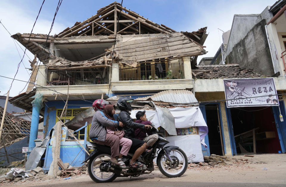 People ride a motorbike past a building damaged in Monday's earthquake in Cianjur, West Java, Indonesia, Tuesday, Nov. 22, 2022. Rescuers on Tuesday struggled to find more bodies from the rubble of homes and buildings toppled by an earthquake that killed a number of people and injured hundreds on Indonesia's main island of Java. (AP Photo/Tatan Syuflana)