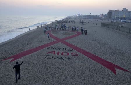 Beach goers look at a red ribbon sand sculpture created by Indian sand artist Sudarshan Patnaik to create awareness about AIDS on the eve of World AIDS Day on a beach in Puri in the eastern Indian state of Odisha November 30, 2014. REUTERS/Stringer