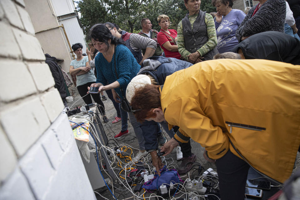 Ukrainian citizens charge their mobile phones and tablets from a generator supplied by Ukrainian soldiers after Russian Forces withdrawal from Izium as the Russia-Ukraine war continues, on Sept 18. Electricity, water and natural gas services are not available in Izium, located in Eastern Ukraine.<span class="copyright">Metin Aktas—Anadolu Agency/Getty Images</span>