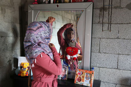 Shorouq Abu Musameh, who volunteers with other paramedics to treat wounded Palestinians participating in protests at the Israel-Gaza border, is reflected in a mirror as she adjusts her head cover in the southern Gaza Strip April 13, 2018. REUTERS/Samar Abo Elouf