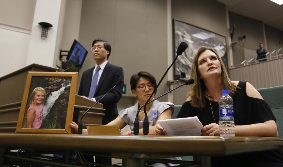 Jenni Balck, right, testifies in support of a measure by state Sen. Richard Pan, D-Sacramento, left, that would give public health officials oversight of doctors that may be giving fraudulent medical expeditions from vaccinations during a hearing of the Assembly Health Committee at the Capitol in Sacramento, Calif., Thursday, June 20, 2019. Balck's daughter, Brooke, seen in photo at left, is a heart transplant recipient who cannot receive immunization shots. (AP Photo/Rich Pedroncelli)