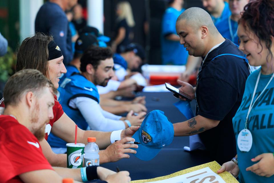 Jaguars quarterback Trevor Lawrence signs a hat for Philip Smith during an autograph session following the team's first training camp practice at the Miller Electric Center.