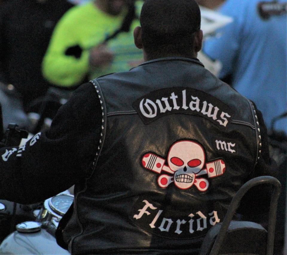 A man wearing an Outlaws Motorcycle Club vest rides down Main Street Saturday, March 2, 2024 during Bike Week in Daytona Beach.