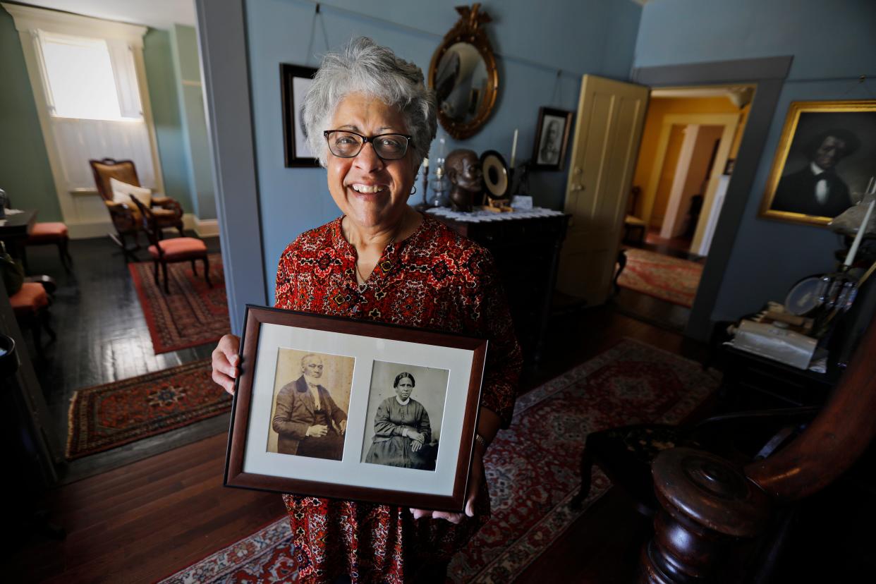 Standing in the entrance to the Nathan & Polly Johnson House in New Bedford, where Frederick Douglass lived during his time in the Whaling City, Lee Blake holds a photo of her two great, great, great grandparents who escaped slavery by boat.