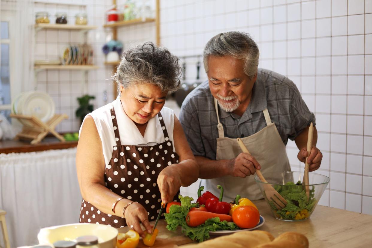 Happiness senior elderly couple having fun in kitchen with healthy food for working from home. COVID-19