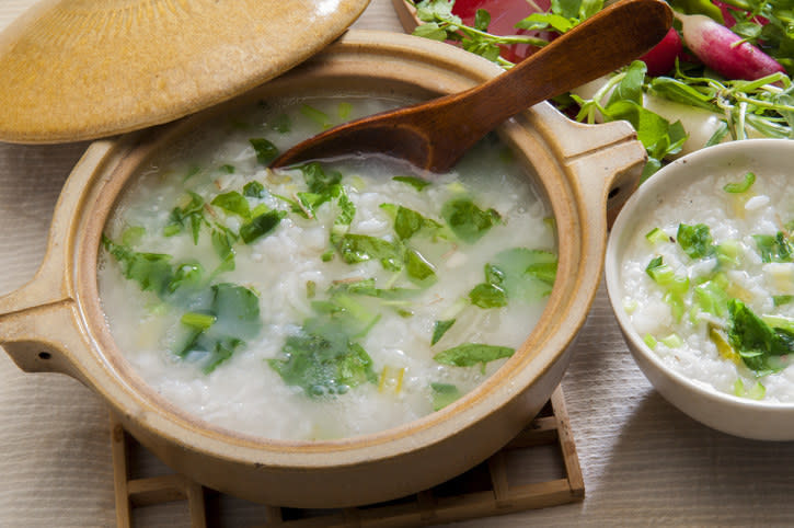 a bowl of congee with green onion and parsley garnishes