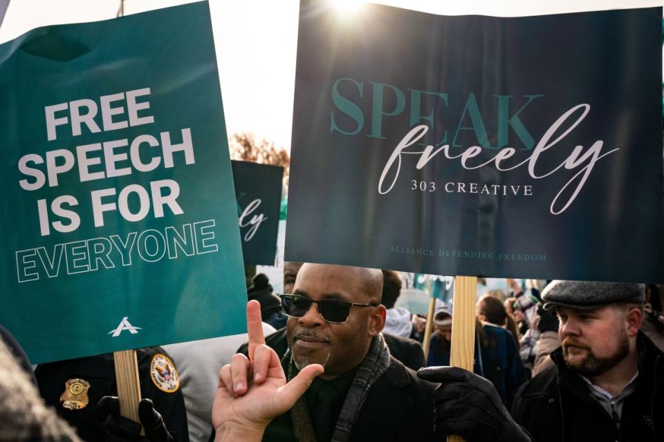 A protester gestures at a man holding signs in support of Lorie Smith/303 Creative