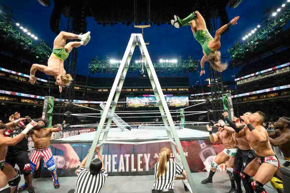 Tyler Bate and Pete Dunne upside down, mid-air, jumping backwards off an A-frame ladder and about to land on competitors during the 6-Pack Ladder Match on Night One WrestleMania 40 at Lincoln Financial Field on April 6, 2024 in Philadelphia, Pennsylvania