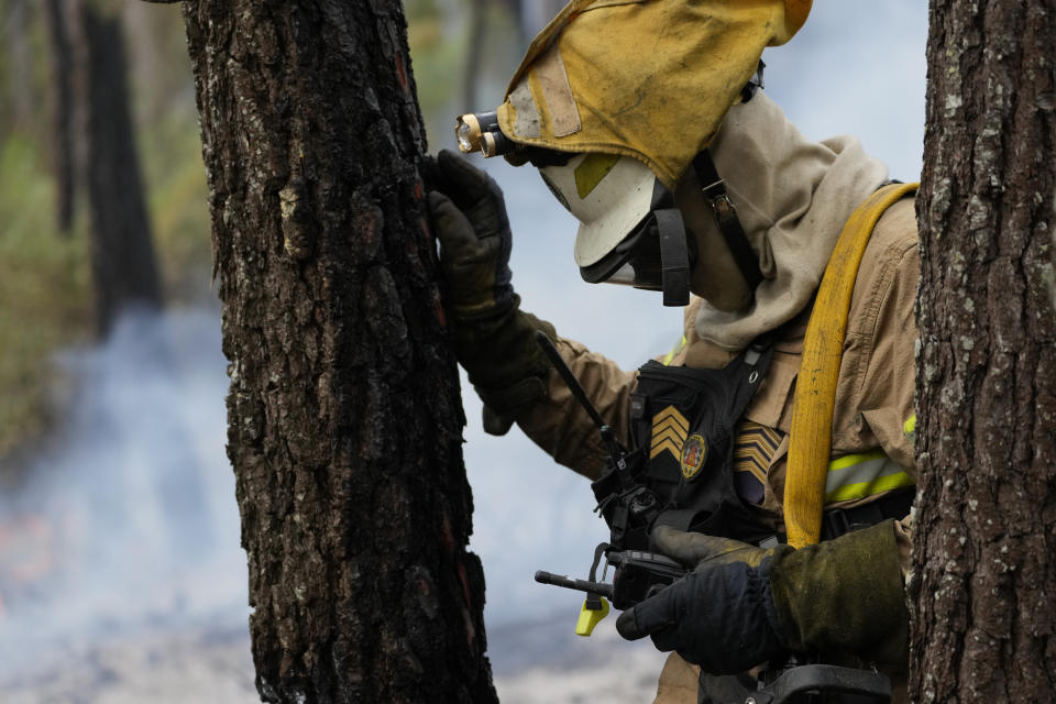 A National Republican Guard firefighter pauses to speak on the radio while putting out a forest fire in the village of Rebolo, near Ansiao central Portugal, Thursday, July 14, 2022. Thousands of firefighters in Portugal have been battling fires all over the country that forced the evacuation of dozens of people from their homes. (AP Photo/Armando Franca)