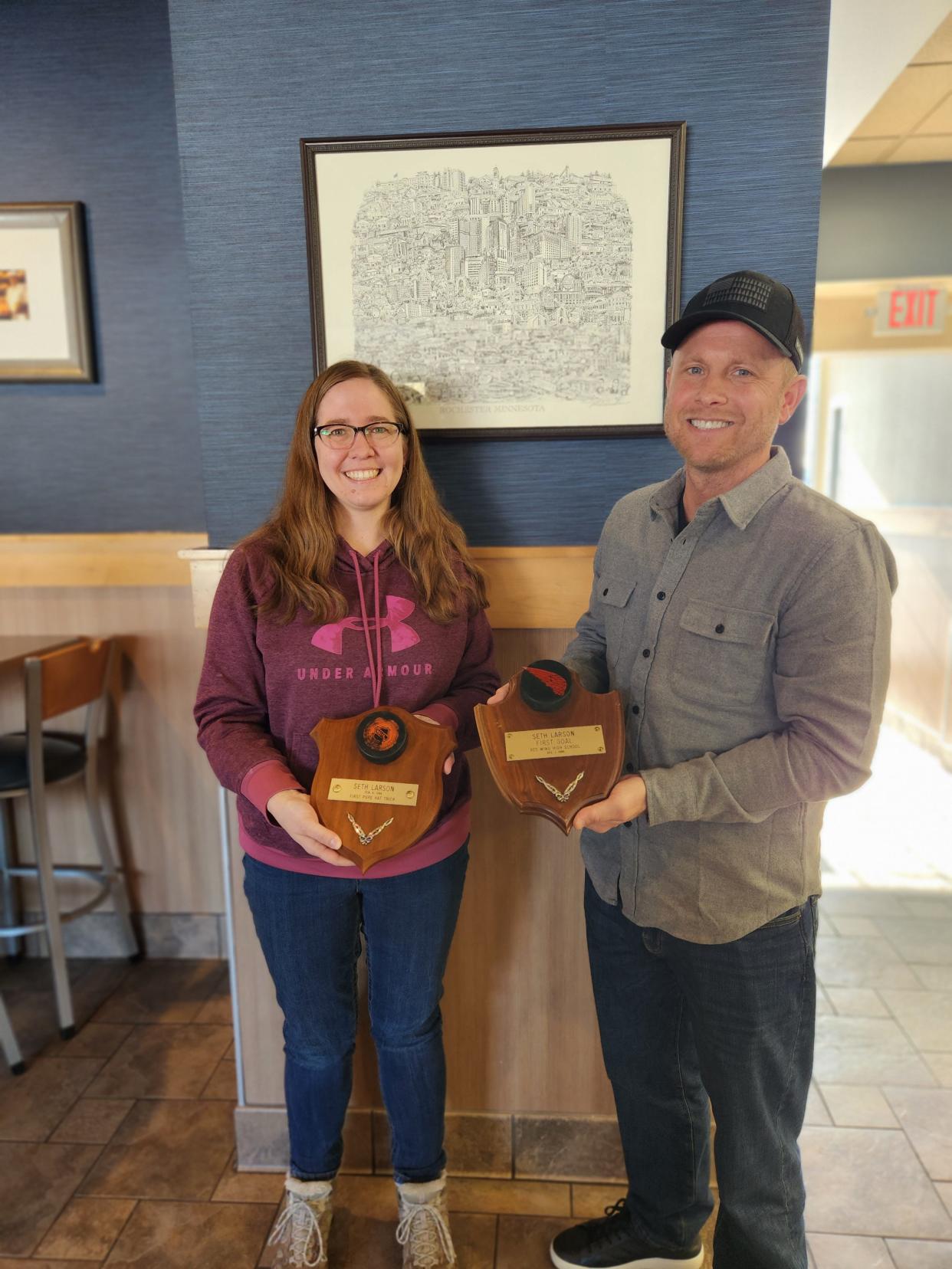 Sarah Cook and Seth Larson hold plaques made by her grandfather honoring Larson's first hockey goal and his first natural hat trick at Red Wing High School in Minnesota. Cook recently discovered the second in the attic of her mother's home in Hager City, Wisconsin, where it had been stored after her grandfather's death, and gave it to Larson over lunch Monday in Rochester, Minnesota.