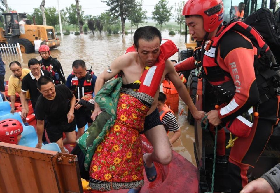 Firefighters use a stretcher to transfer an elderly man from Shuiyuzui Village in flood-hit Mentougou District on August 1, 2023 in Beijing, China.