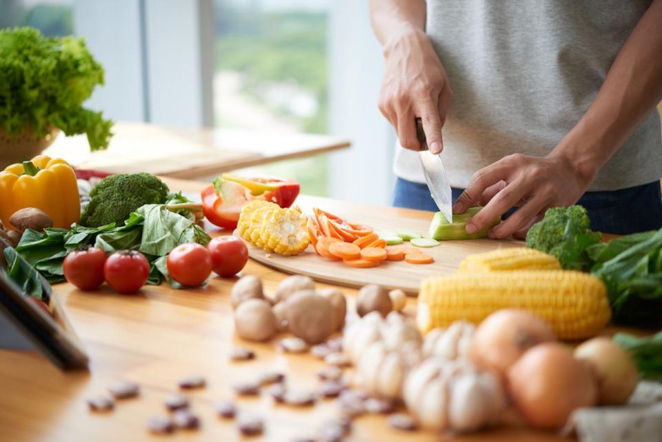 A man slices vegetables on a kitchen counter. 