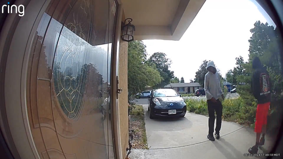 Two people in hoods standing near a home's front door