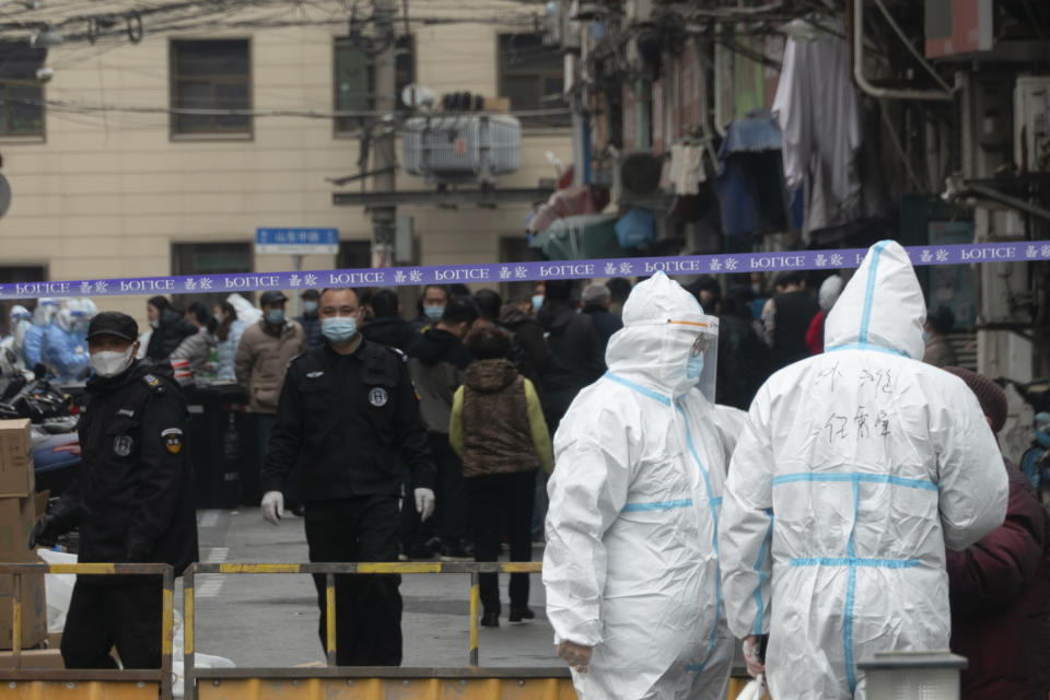 Police officers and workers in protective suits close off a neighborhood as it is placed under lockdown in Shanghai, China, Thursday, Jan. 21, 2021. Shanghai has imposed lockdowns on two of China's best-known hospitals and some surrounding residential communities after they were linked to new coronavirus cases. (Chinatopix via AP)