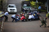 People take cover after an attack on a hotel, in Nairobi, Kenya, Tuesday, Jan. 15, 2019. Extremists launched a deadly attack on a luxury hotel in Kenya's capital Tuesday, sending people fleeing in panic as explosions and heavy gunfire reverberated through the complex. A police officer said he saw bodies, "but there was no time to count the dead." (AP Photo/Brian Inganga)