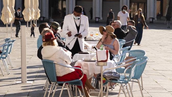 Waiters melayani turis yang duduk di teras kafe Piazza San Marco di Venesia. (Marco Bertorello/AFP)