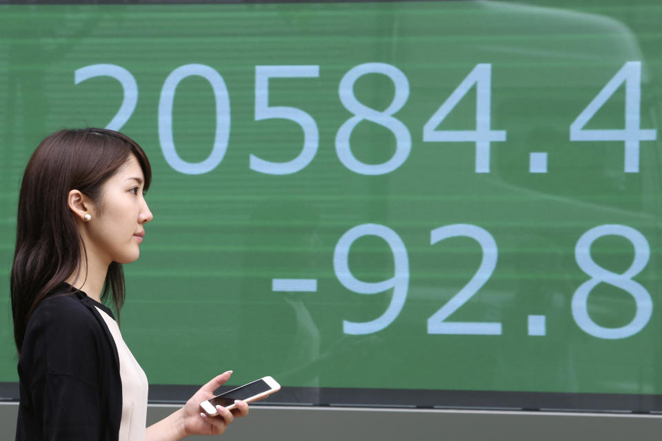 A woman walks by an electronic stock board of a securities firm in Tokyo, Wednesday, Aug. 21, 2019. Asia stock markets followed Wall Street lower Wednesday as investors looked ahead to a speech by the Federal Reserve chairman for signs of possible plans for more U.S. interest rate cuts. (AP Photo/Koji Sasahara)