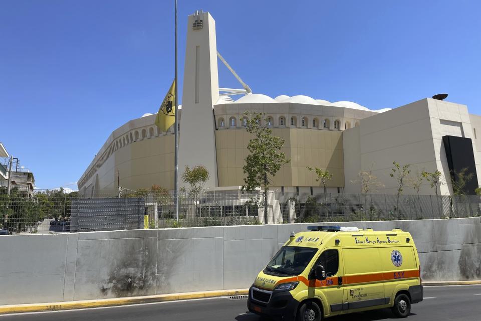 An AEK Athens team flag is at half staff outside OPAP Arena as an ambulance drives past, following overnight clashes between rival supporters in Nea Philadelphia suburb, in Athens, Greece, Tuesday, Aug. 8, 2023. European governing soccer body UEFA says it has postponed a Champions League qualifying game between AEK Athens and Croatia's Dinamo Zagreb scheduled for Tuesday because of the violence. Eight fans were injured while Greek police said Tuesday they had made 88 arrests, mostly of Croatian supporters. (AP Photo/Thanassis Stavrakis)