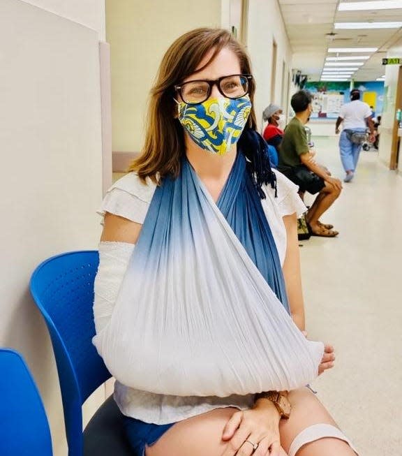 Woman with facemask and arm sling in a hospital.