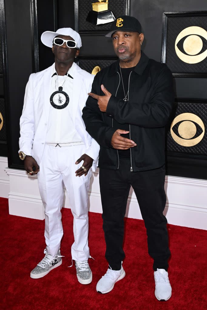 Flavor Flav in all-white with gray sneakers and Chuck D in black.