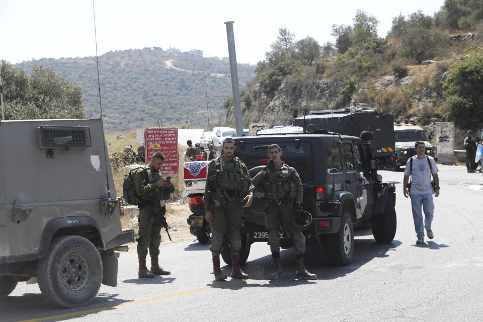 Israeli soldiers secure an area near Dolev settlement in the West Bank, Friday, Aug. 23, 2019, after three Israelis were wounded in an explosion. The Israeli military said it suspects the explosion near Dolev settlement, northwest Jerusalem, to be a Palestinian attack. (AP Photo/Mahmoud Illean)