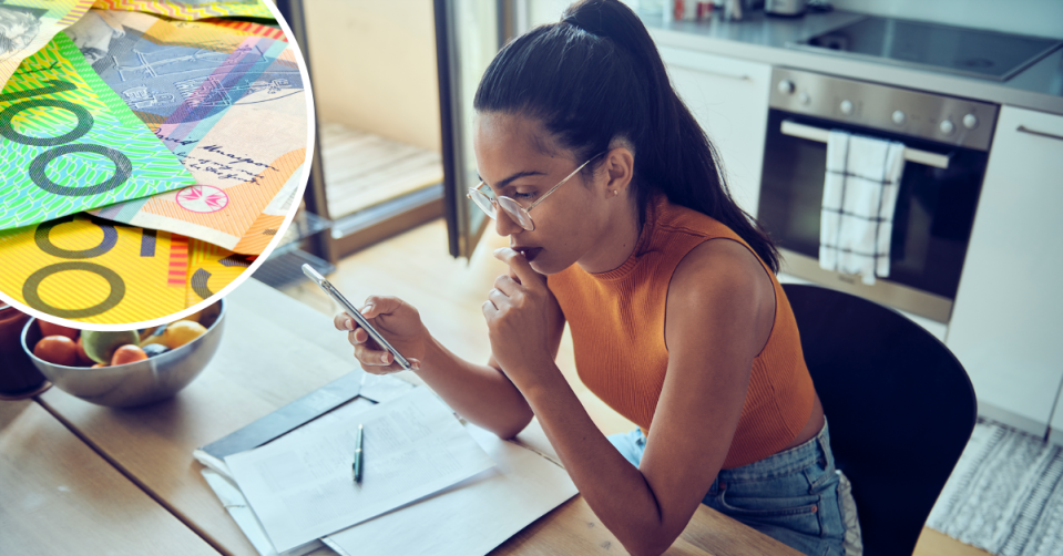 Australian cash. Young woman looks at her finances in her kitchen