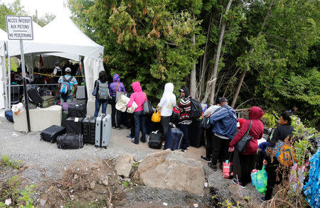 FILE PHOTO: A line of asylum seekers who identified themselves as from Haiti wait to enter into Canada from Roxham Road in Champlain, New York, U.S., August 7, 2017. REUTERS/Christinne Muschi/File Photo