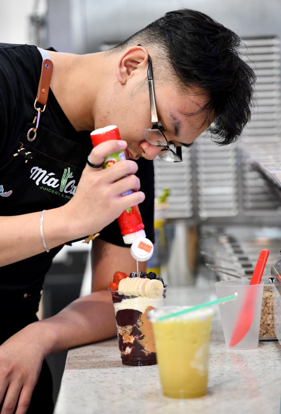 Mia Cane Juicery & Acai Bar employee Ryan Luu of Worcester prepares an acai cup.