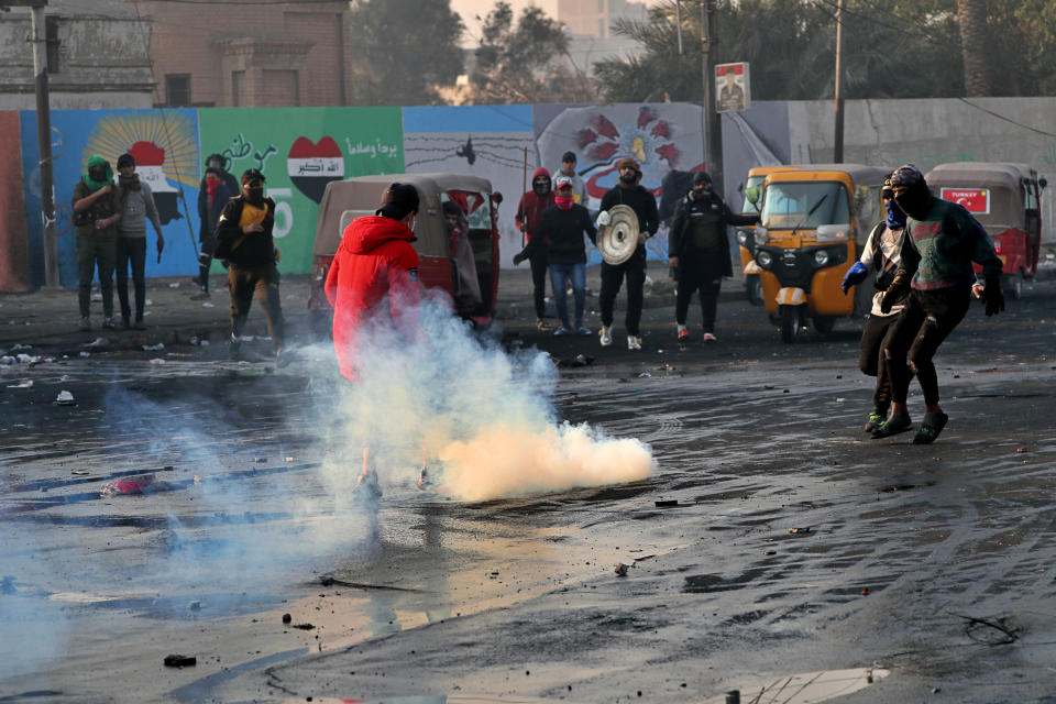 Protesters grab tear gas canisters during ongoing protests in central Baghdad, Iraq, Monday, Jan. 20, 2020. (AP Photo/Khalid Mohammed)