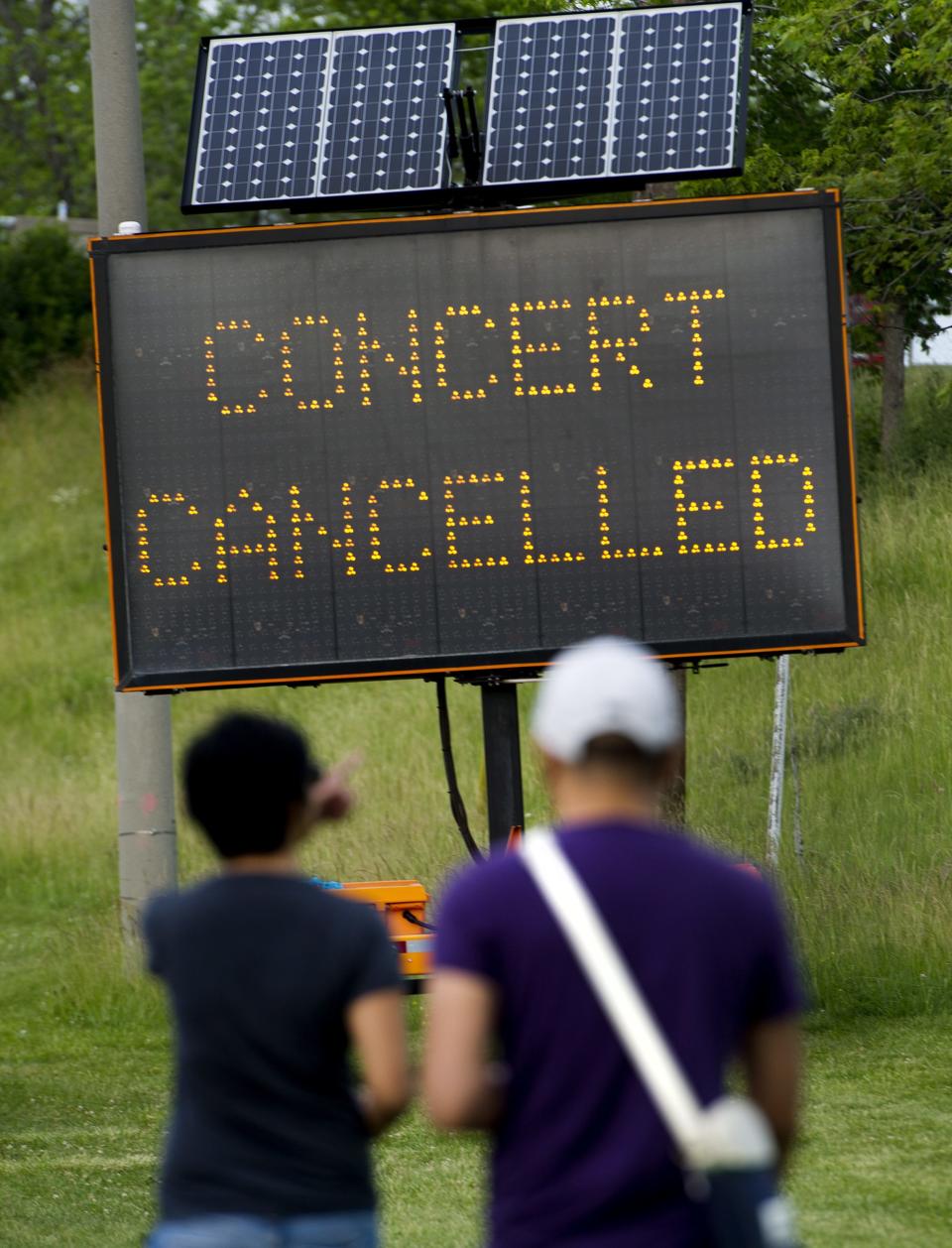 People read a sign informing of the cancellation of a Radiohead concert after a stage collapsed at Downsview Park in Toronto on Saturday, June 16, 2012. Toronto paramedics say one person is dead and another is seriously hurt after the stage collapsed while setting up for a Radiohead concert. They say two other people were injured and are being assessed. (AP Photo/The Canadian Press, Nathan Denette)