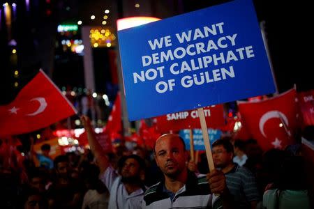 A man holds a banner as he and others have gathered in solidarity night after night since the July 15 coup attempt in central Ankara, Turkey, July 27, 2016. REUTERS/Umit Bektas