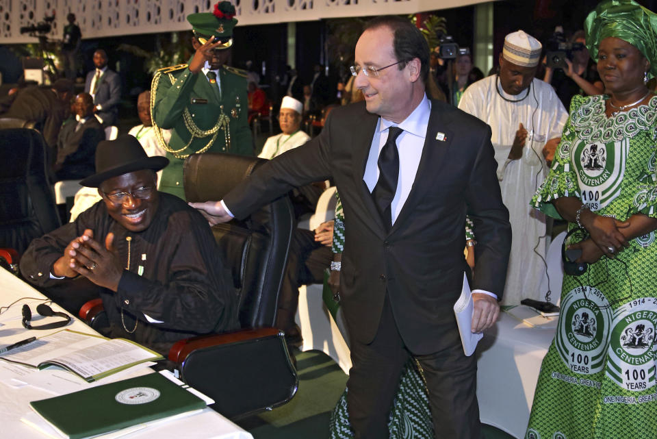 French President Francois Hollande, center, walks past Nigerian President Goodluck Jonathan to deliver a speech during the International Conference on Peace and Security in Abuja, Nigeria, as part of its Centenary celebrations, Thursday, Feb. 27, 2014. Hollande is in Nigeria for a one-day official visit. (AP Photo/Philippe Wojazer, Pool)