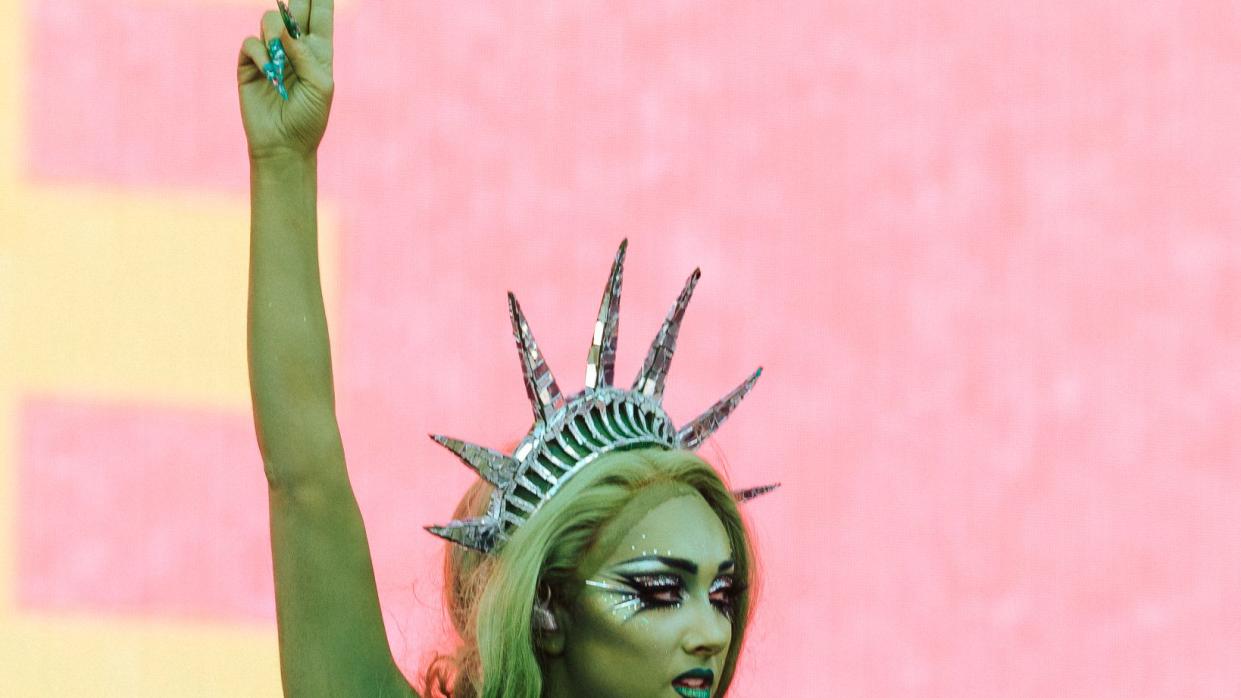 a person with green hair and a microphone with the arms raised