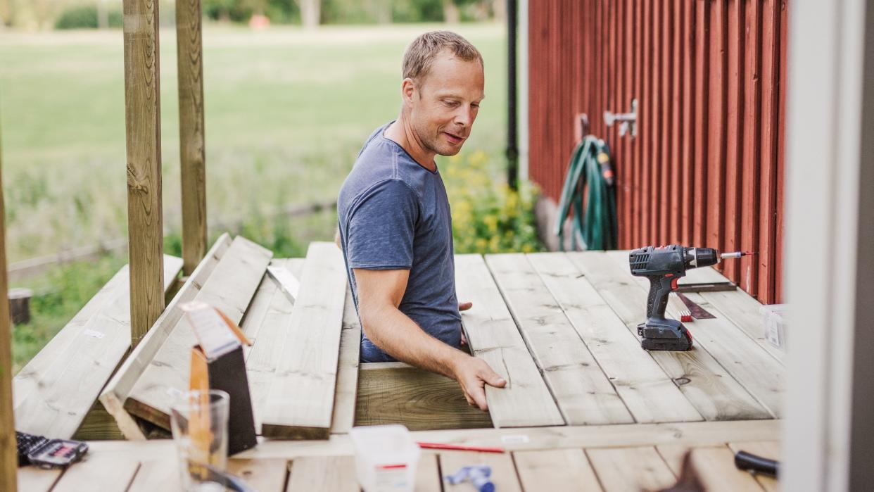 Man building a patio outside his country side house.