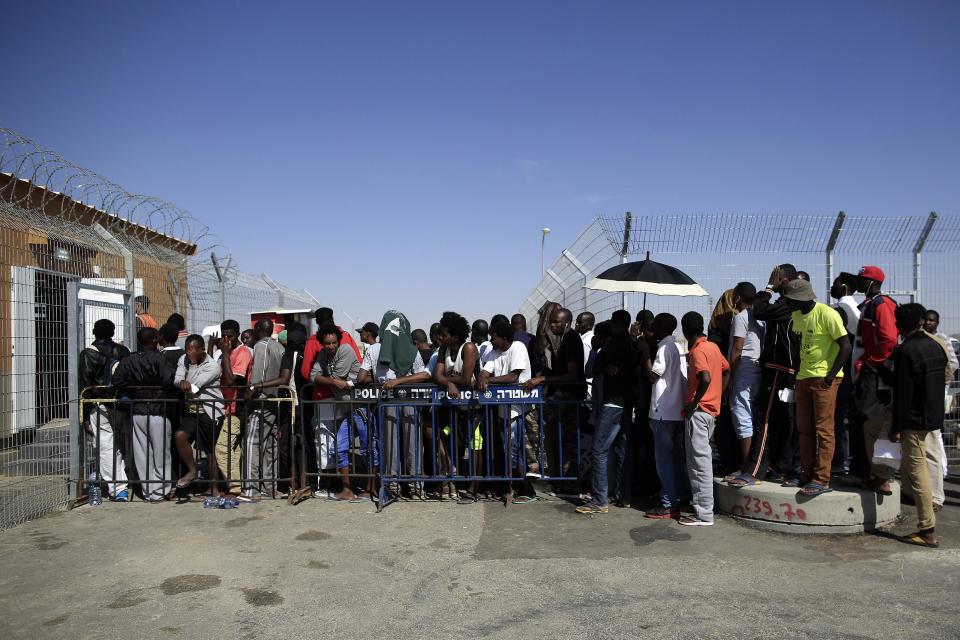 African migrants enter the Holot detention center, southern Israel, Friday, April 11, 2014. Hundreds of African migrants gathered outside the Holot detention center in Israel’s Negev desert on Friday to eat matzo and recall the Passover story - one of freedom from bondage - mere steps away from a detention facility where they are being held. (AP Photo/Tsafrir Abayov)