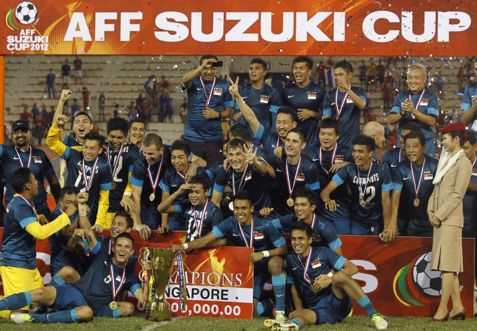 Singapore's team player and staff celebrate with the trophy after their AFF Suzuki Cup 2012 win over Thailand at Supachalasai National Stadium in Bangkok December 22, 2012. REUTERS/Chaiwat Subprasom   (THAILAND - Tags: SPORT SOCCER)