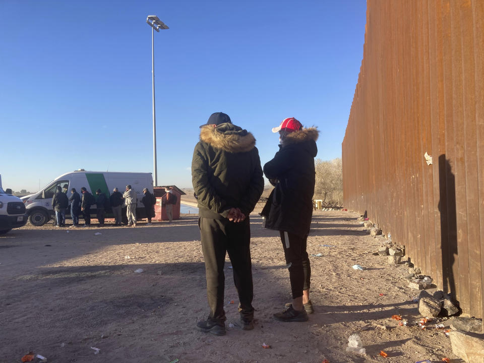 Two Indian migrants wait to be escorted to a Border Patrol van in Yuma, Ariz., Saturday, Feb. 5, 2022, after crossing the border illegally from Los Algodones, Mexico. For nationalities that don't need a visa, Mexico is often the ticket to seeking asylum in the United States. (AP Photo/Elliot Spagat)