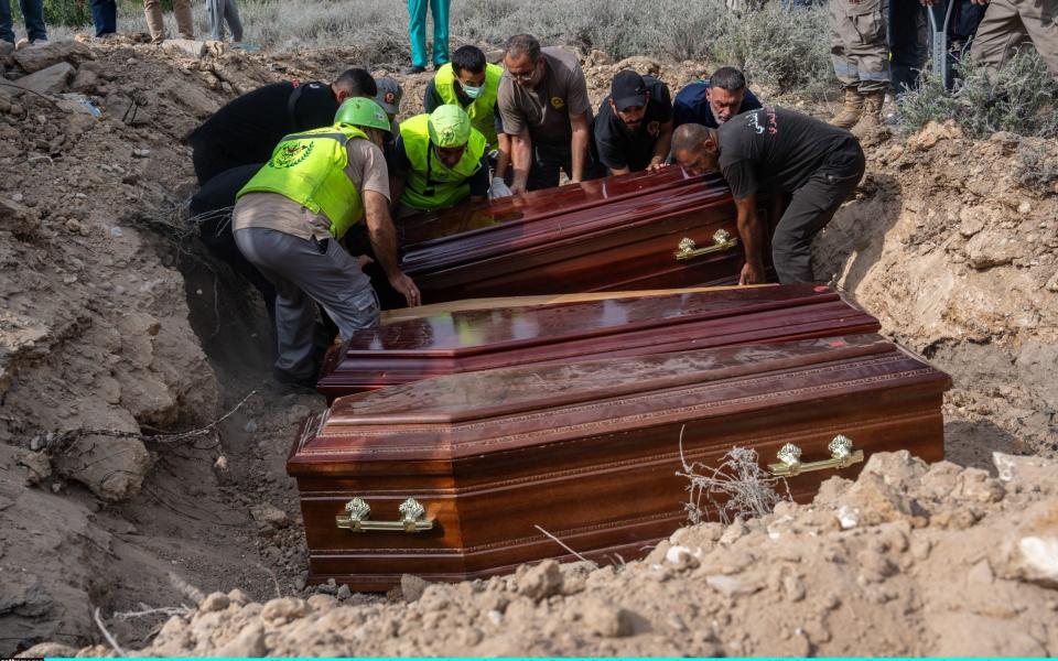 A coffin is lowered into the ground at a funeral for five civil defence workers who were killed in an Israeli attack on the southern Lebanese village of Derdghaiya near Tyre.