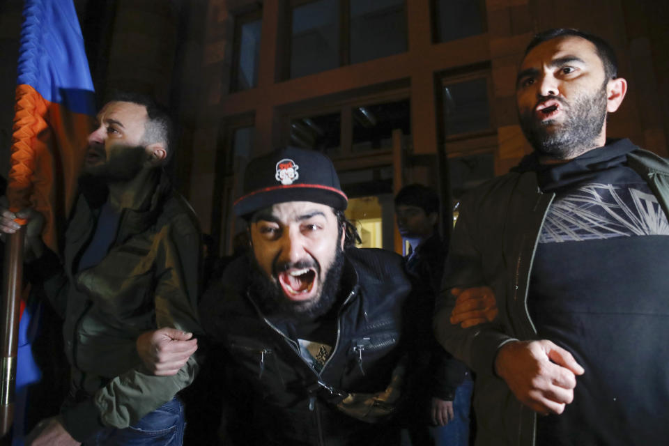 Protesters shout as they protest against an agreement to halt fighting over the Nagorno-Karabakh region, at the government building in Yerevan, Armenia Tuesday, Nov. 10, 2020. Armenia and Azerbaijan announced an agreement early Tuesday to halt fighting over the Nagorno-Karabakh region of Azerbaijan under a pact signed with Russia that calls for deployment of nearly 2,000 Russian peacekeepers and territorial concessions. (AP Photo/Dmitri Lovetsky)