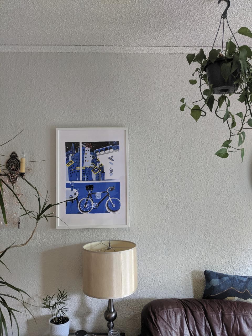 This July 29, 2019 photo provided by Holly Oehme shows borrowed art hanging on the wall of her home in Minneapolis. Oehme loves borrowing art from the Minneapolis Art Lending Library and has a dedicated space for the pieces. The art shown here is by Xiaojie Liu and is titled "One Night in Minneapolis," 2018. (Holly Oehme via AP)