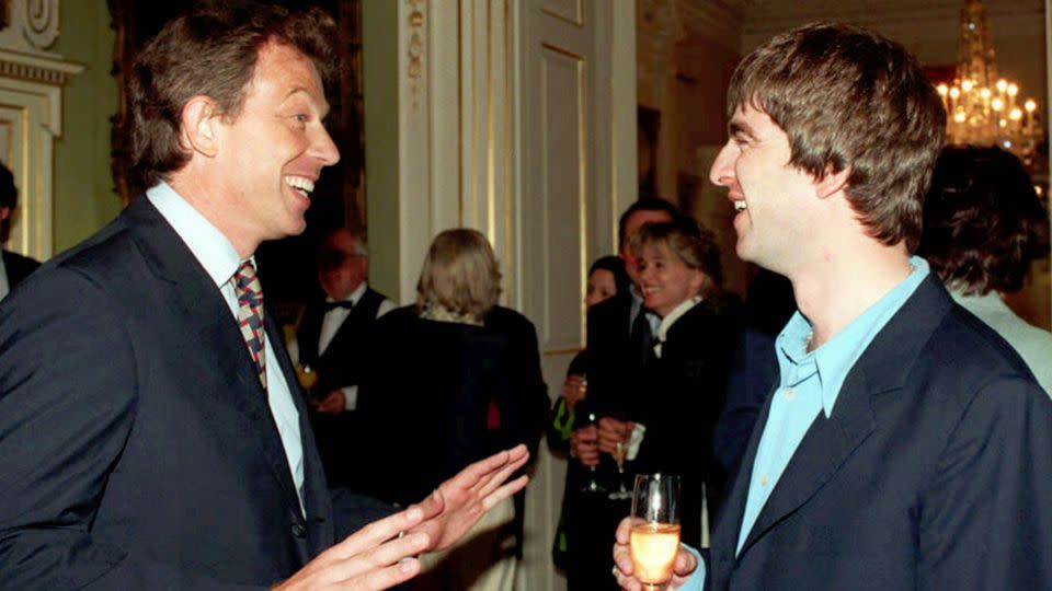 Then-British Prime Minister, Tony Blair, greets Oasis singer-songwriter Noel Gallagher during a Downing Street reception in July, 1997. The economic and cultural optimism around New Labour in the second-half of the 1990s became known as 'Cool Britannia.' - Rebecca Naden/PA/AP