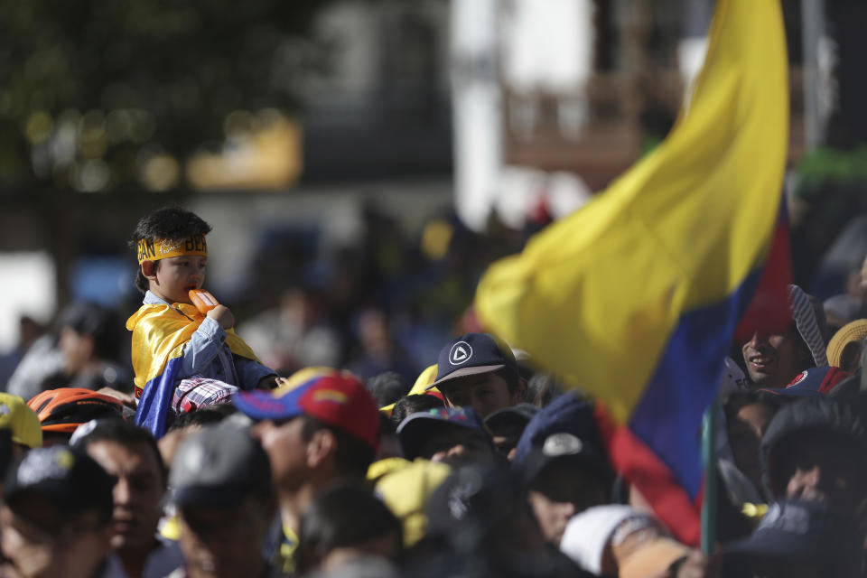 A child eats a popsicle as he awaits the arrival of Tour de France winner Egan Bernal to Zipaquira, Colombia, Wednesday, Aug. 7, 2019. Bernal rode into the town's central square on his bike on wearing the Tour de France's iconic yellow jersey. A group of some 3,000 supporters dressed in the same color chanted his name. (AP Photo/Ivan Valencia)